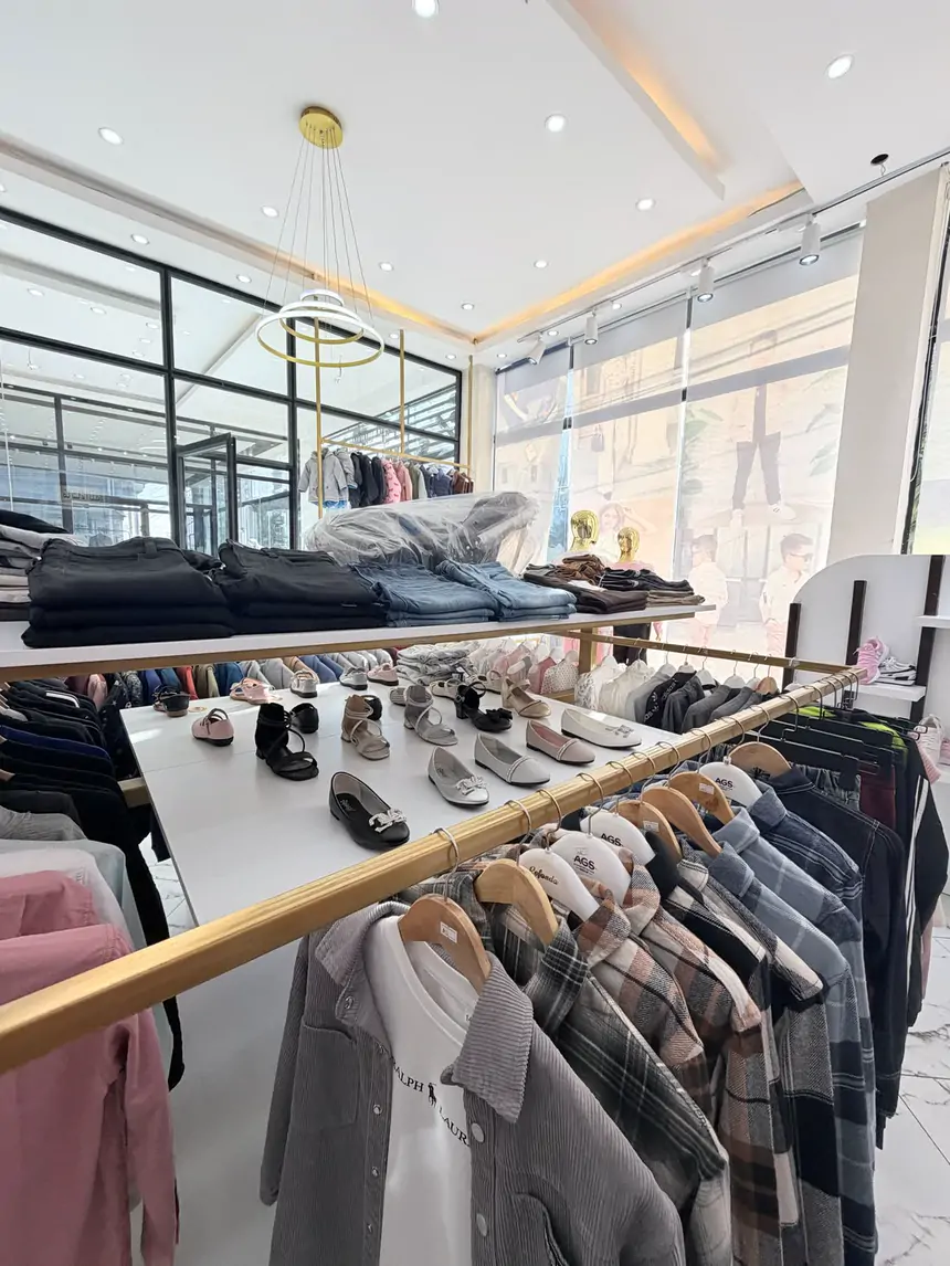 Checked shirts and jackets on a gold rail with folded jeans and little shoes behind