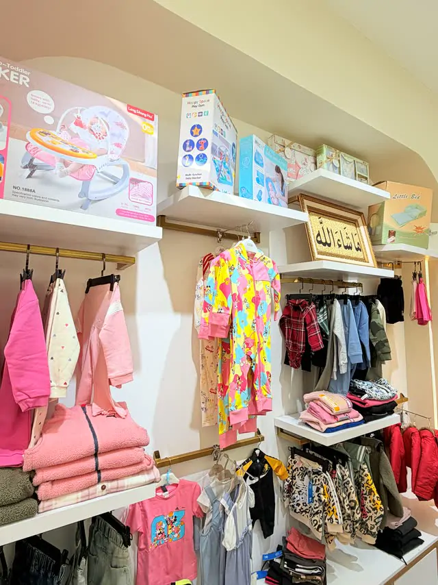 Soft pink baby outfits, rompers and rockers on arched shelves