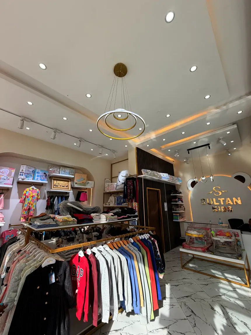 Inside Sultan Kids: a gold ring chandelier, gold rails full of clothes and the gold sign on the bear-shaped wall